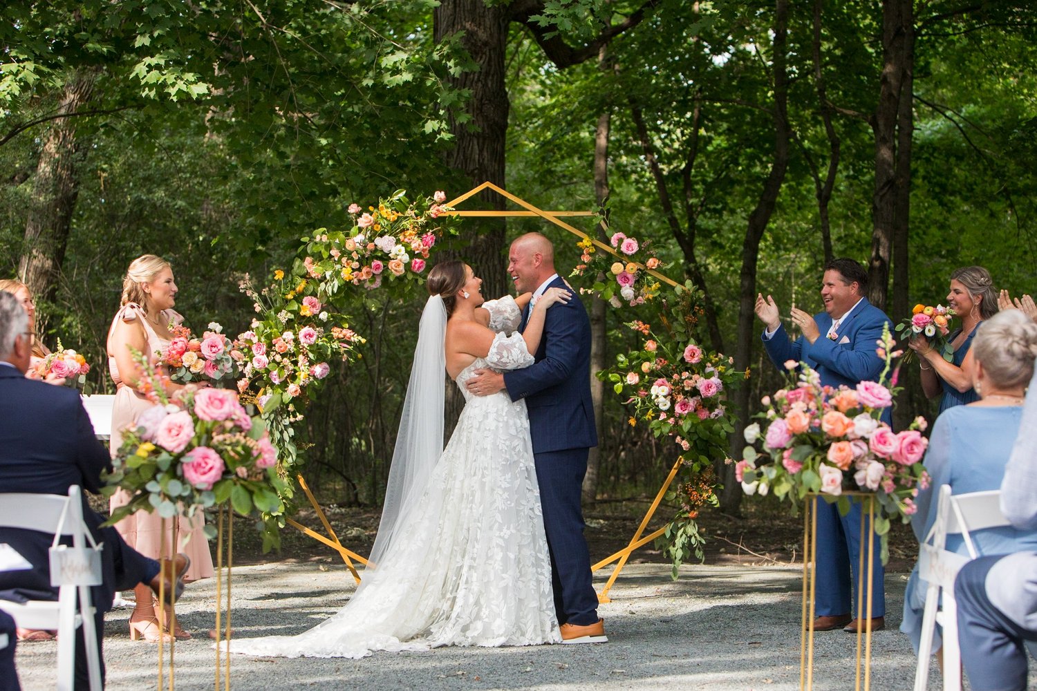 Forest ceremony framed by a floral arch